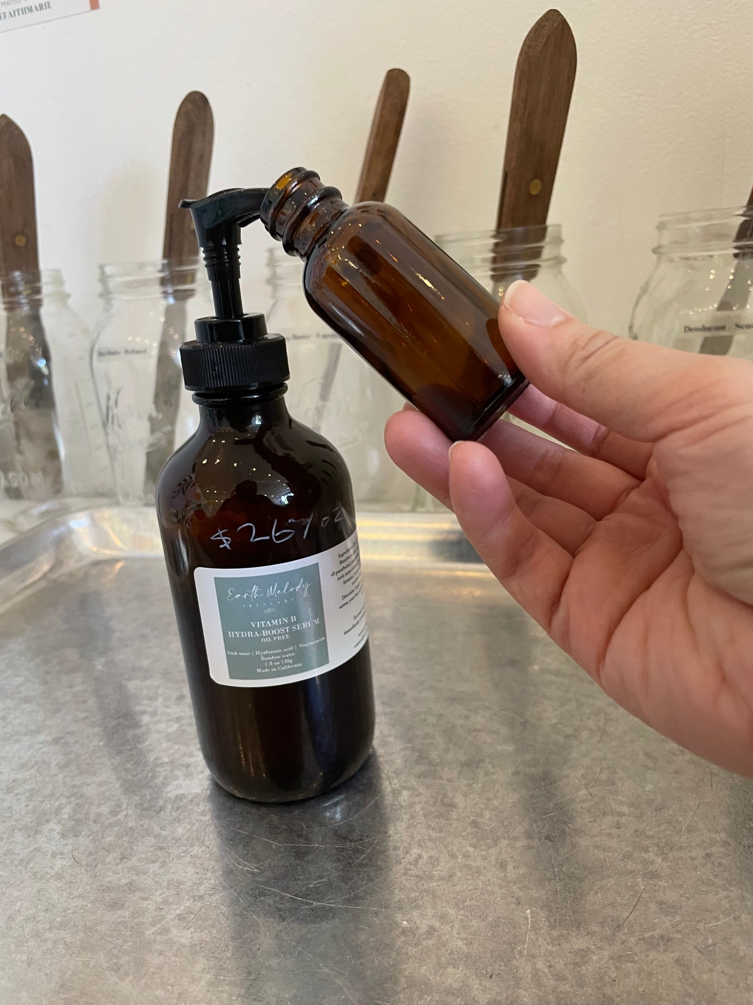 Hand holding a brown bottle with a pump on a light-colored surface